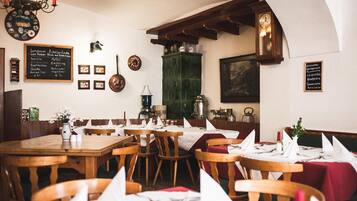 Ein Restaurantinneres mit Holztischen und -stühlen, einer Kreidetafel mit der Speisekarte und verschiedenen Wanddekorationen.