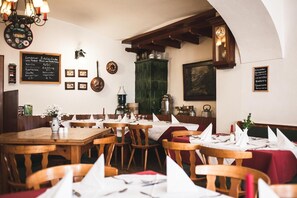 L’intérieur d’un restaurant avec des tables et des chaises en bois, un menu écrit à la craie et diverses décorations murales.