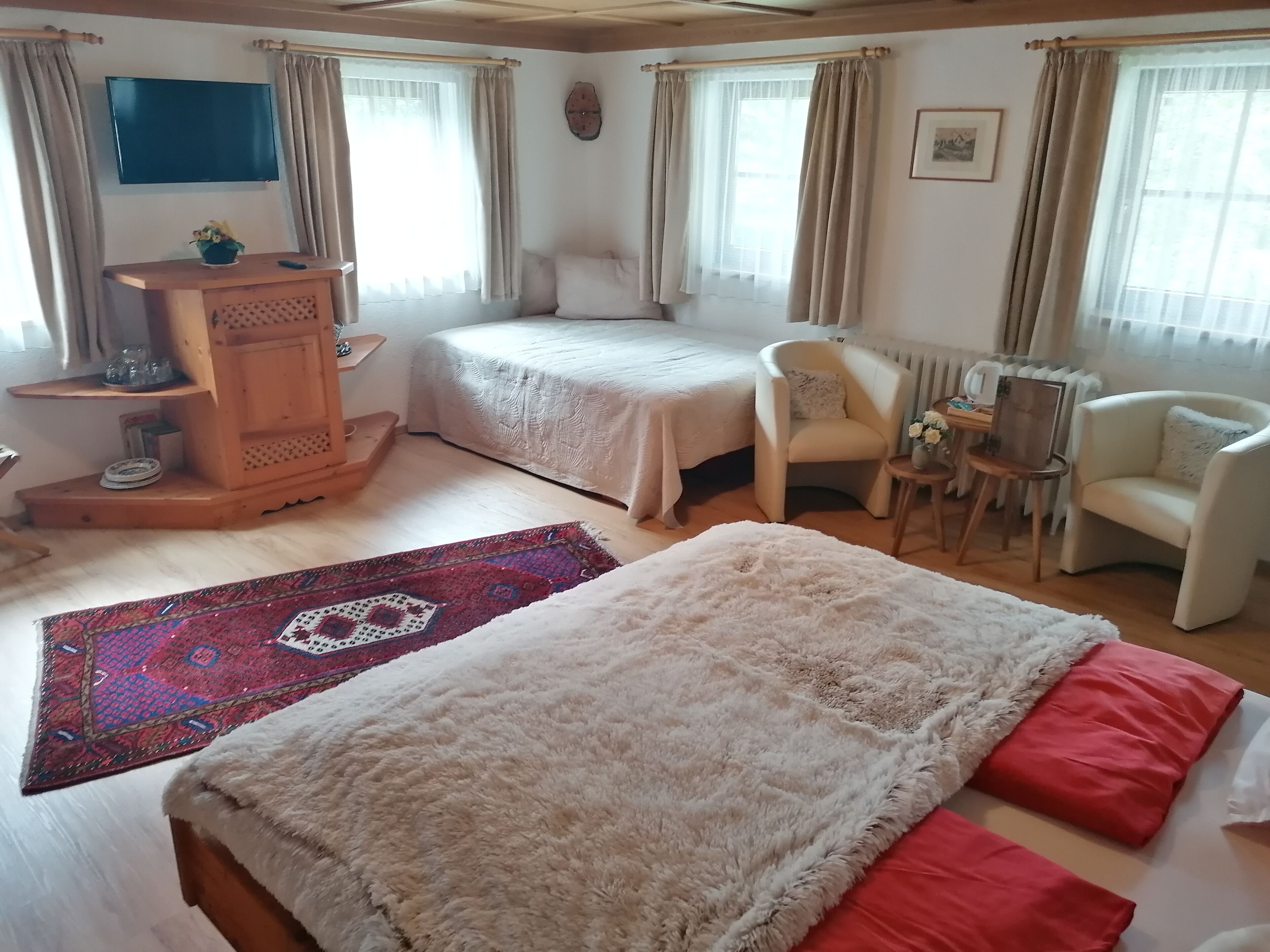 Een slaapkamer met twee bedden, een houten nachtkastje, een stoel, een klein tafeltje en een radiator.