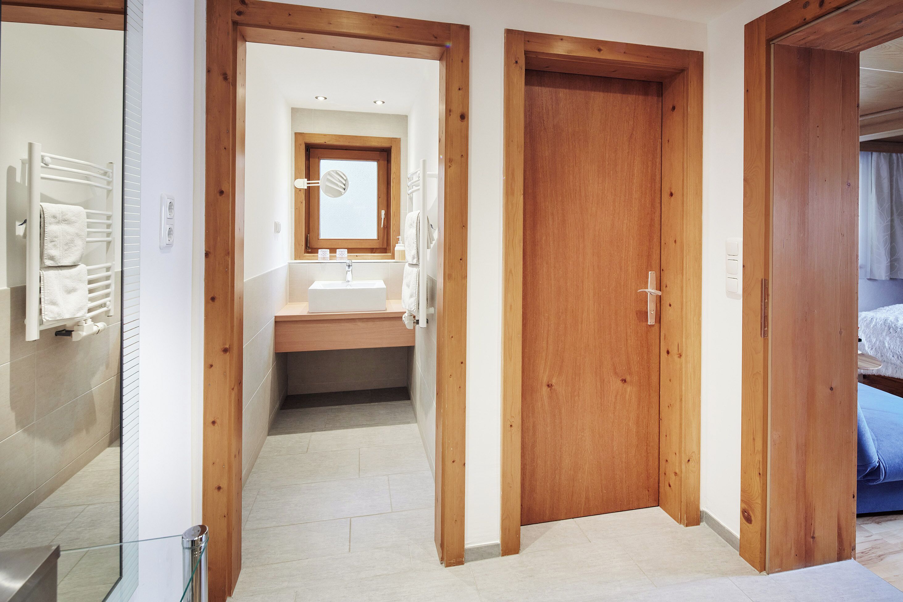 A modern bathroom with a glass shower, wooden door frames, and a visible sink area.