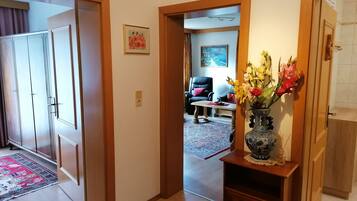 Ein Flur mit einer Holztür, einem Blumenstrauß in einer Vase und einem Gemälde an der Wand.