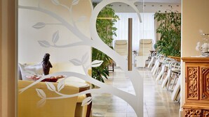 Uma sala de estar moderna com uma parede branca decorativa curva, um sofá amarelo e uma área de jantar com cadeiras e uma mesa.