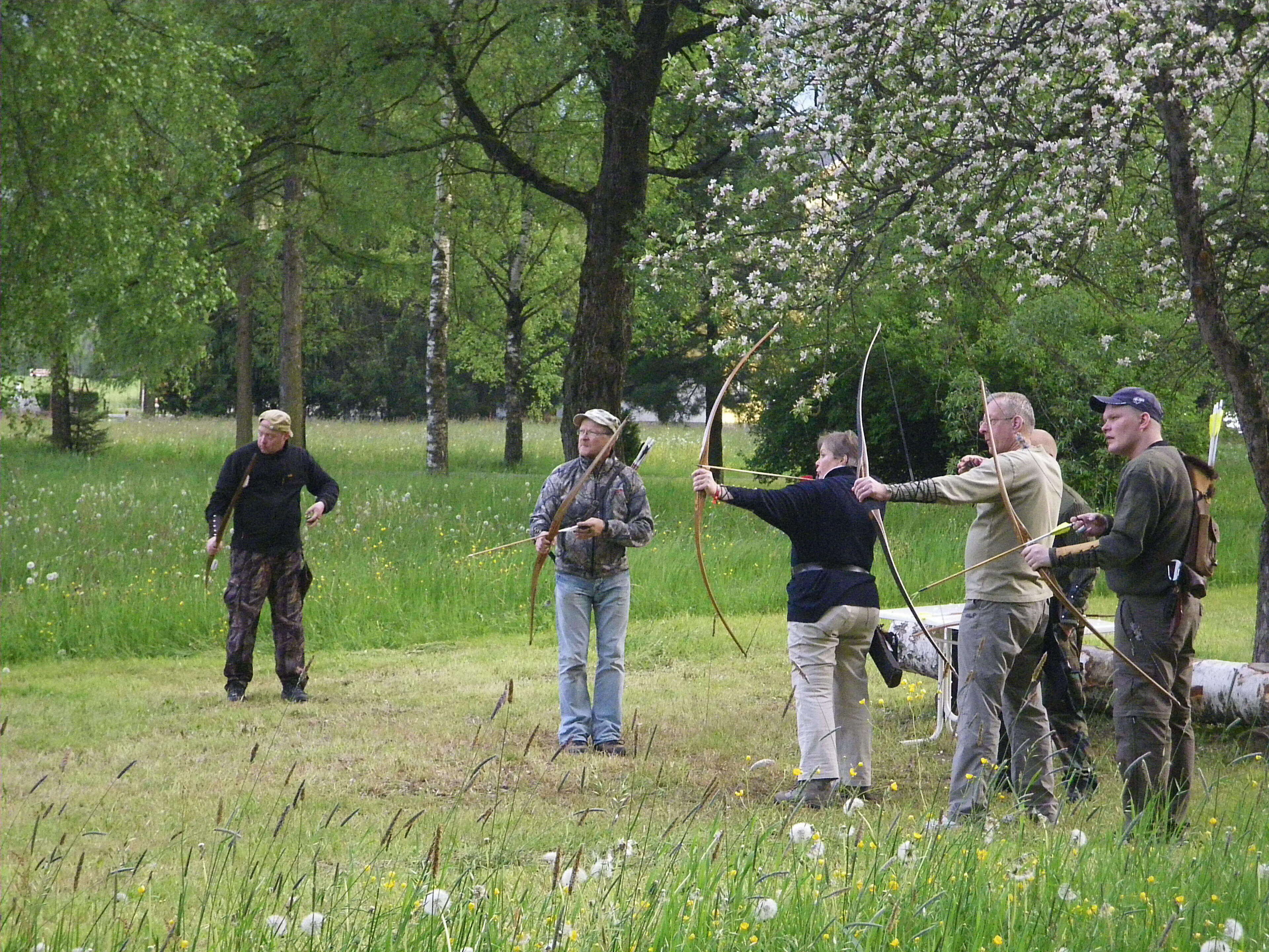 A group of people in an outdoor setting with trees and grass.