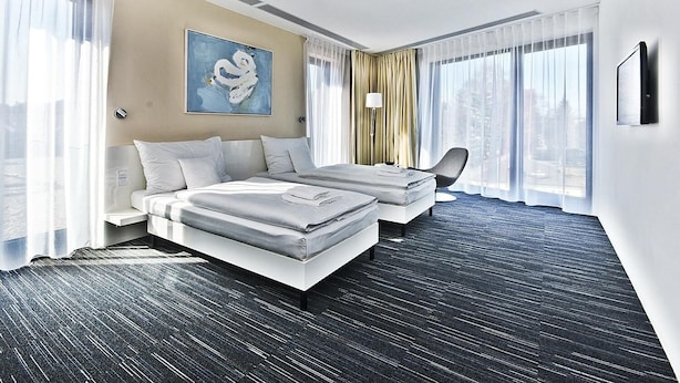 Habitación de hotel con una cama grande, un sofá cama, un televisor de pantalla plana y un cuadro en la pared.