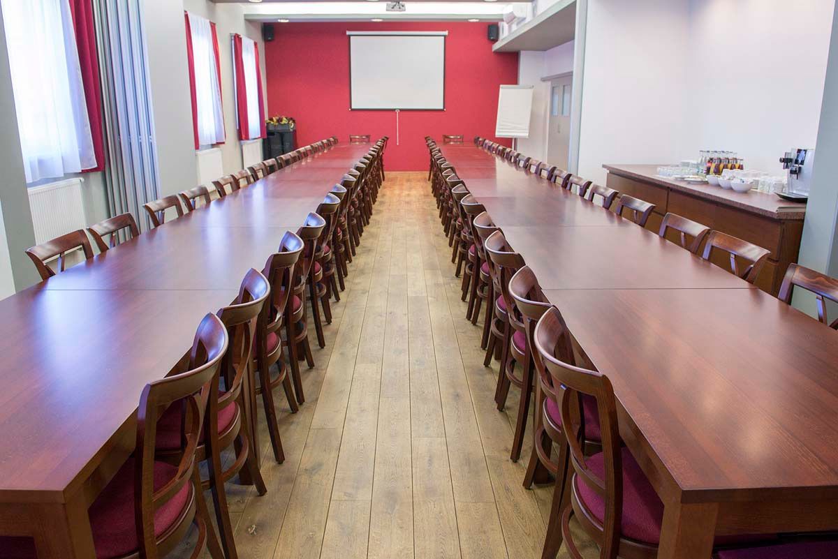 A conference room with a long table and chairs, a projector screen, and a whiteboard.