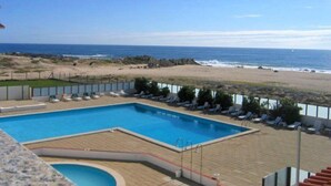 Ein Poolbereich mit Blick auf Strand und Meer.