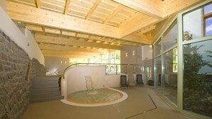 A spa area with a stone wall, wooden ceiling, and a glass enclosure with a water feature.