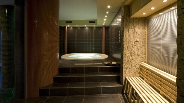 A spa area with a hot tub, stone walls, and a wooden bench.