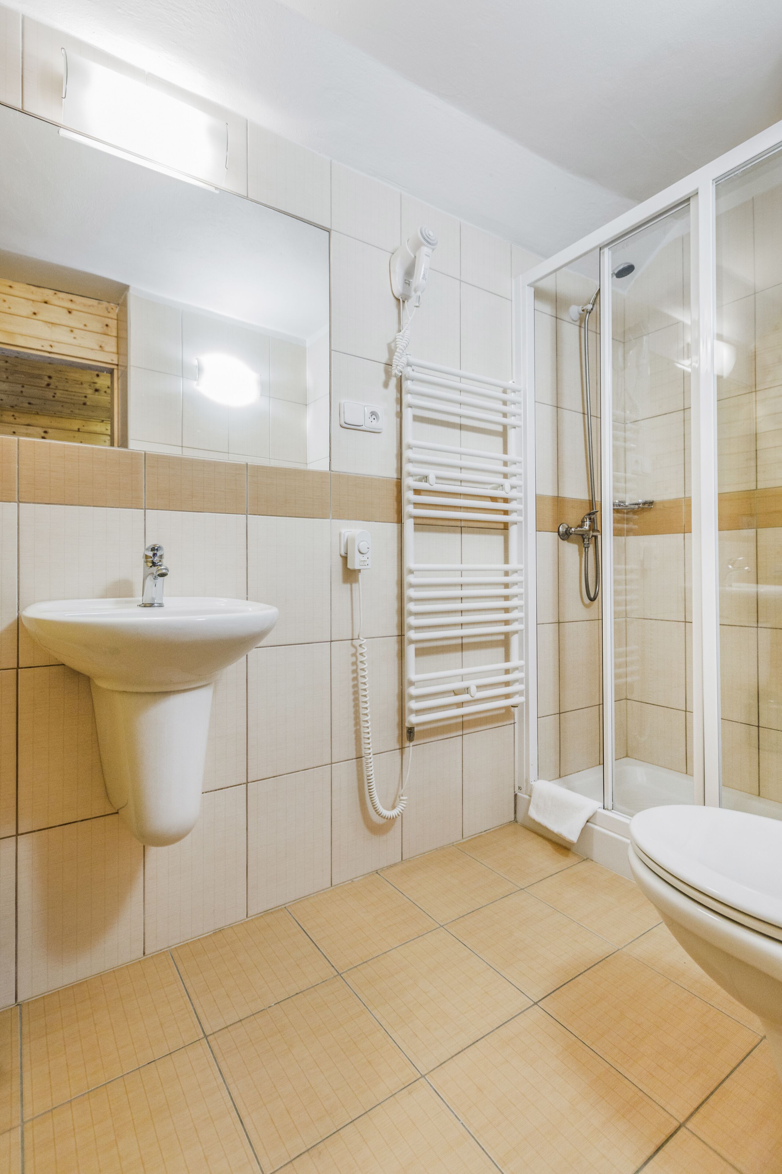 A bathroom with a sink, a towel rack, a glass-enclosed shower, and a toilet.