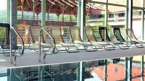 A pool area with lounge chairs and a wooden ceiling.