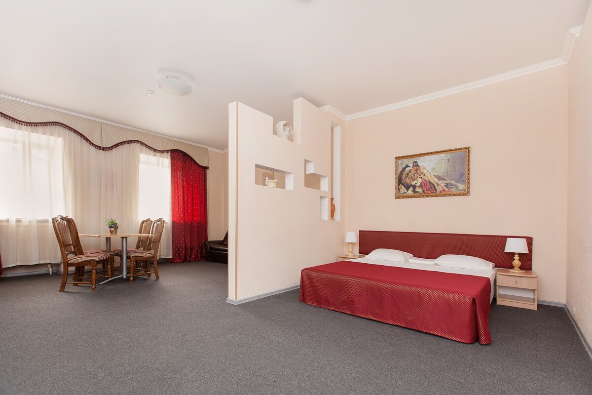 Una habitación de hotel con cama, escritorio, silla y un cuadro en la pared.