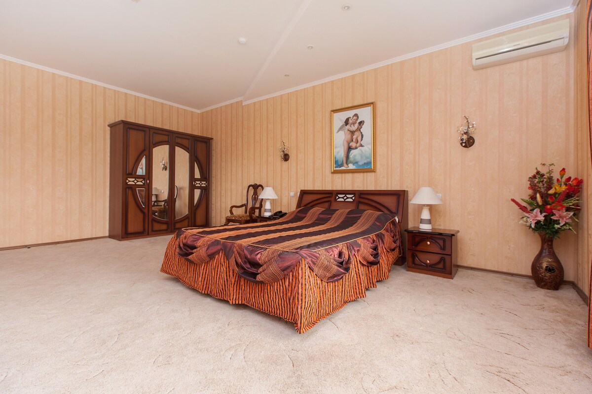 Un dormitorio con una cama grande, un armario de madera y un cuadro en la pared.