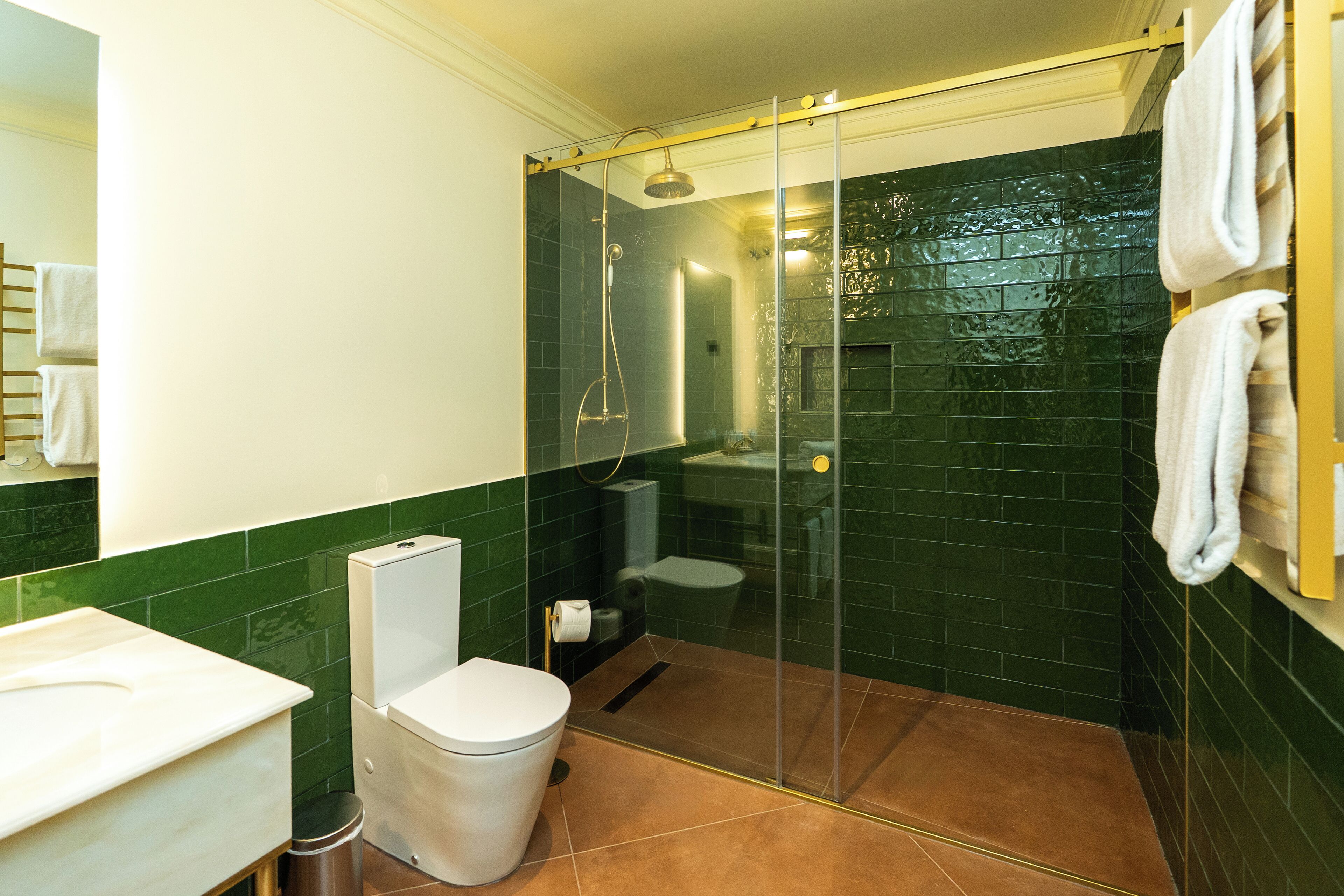 A bathroom with a glass-enclosed shower, a toilet, and a sink.