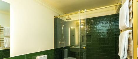 A bathroom with a glass-enclosed shower, a toilet, and a sink.