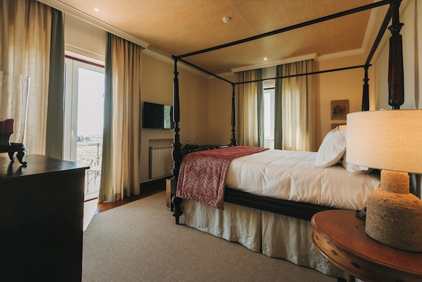 A four-poster bed with a red throw blanket, a bedside lamp, and a view of the outdoors through a large window. - The Manor House Celeirós (Sabrosa)