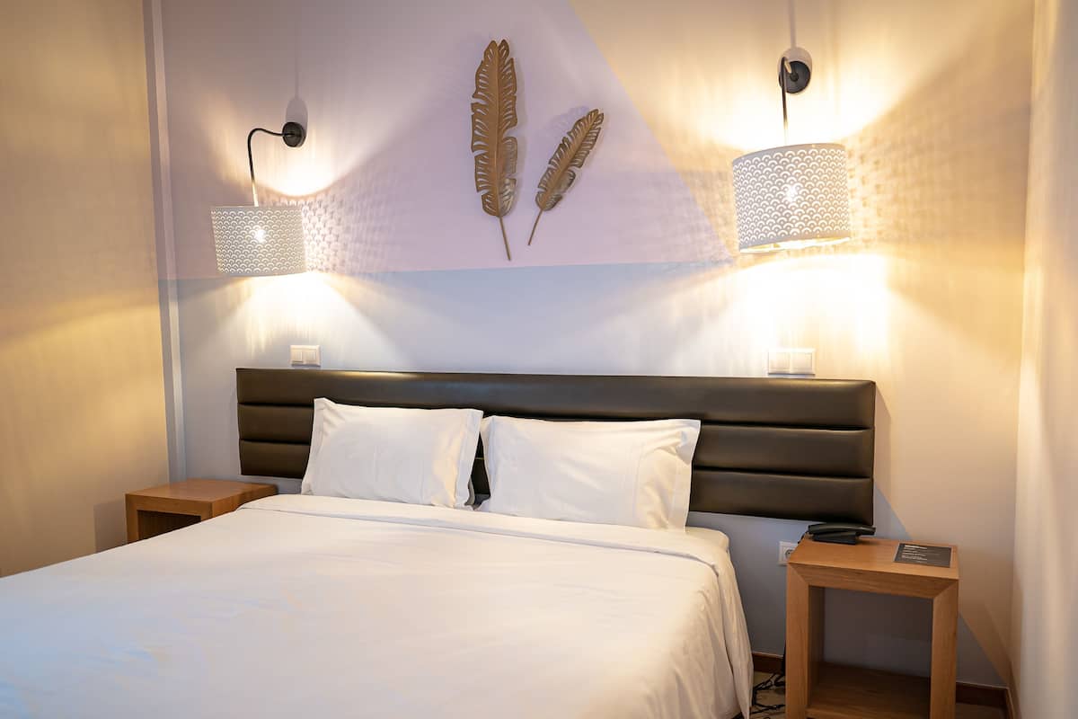 Een slaapkamer met een bed, twee nachtkastjes en wandlampen.