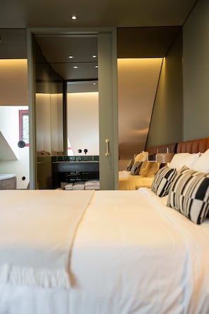 Ein modernes Hotelzimmer mit einem großen Bett, einem Badezimmer mit Spiegel und Blick auf den Himmel.