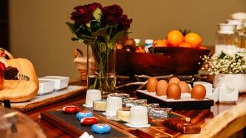 Ein reichhaltiges Buffet mit verschiedenen Speisen, einer Rosenvase und einer Schüssel Orangen.