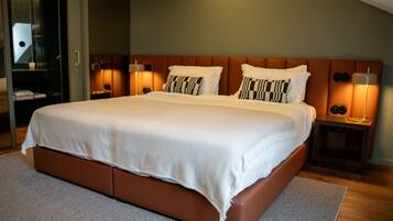 Una cama grande con cabecera de madera, dos lámparas de noche y un tapete de color neutro.