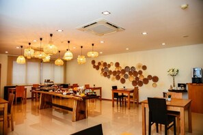 A spacious dining area with multiple tables and chairs, overhead lighting, and a wall decorated with circular plates. - Santo Thyrso Hotel (Santo Tirso)