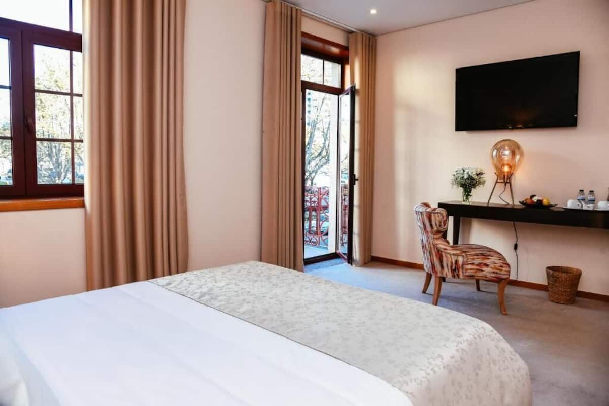 Een hotelkamer met een bed, een bureau met stoel, een televisie en uitzicht door een glazen deur.