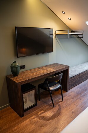 A modern room with a wooden desk, a chair, a television mounted on the wall, and a staircase in the background. - Santo Thyrso Hotel (Santo Tirso)