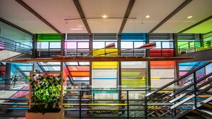 A modern interior with a central staircase, glass railings, and a plant in the foreground.
