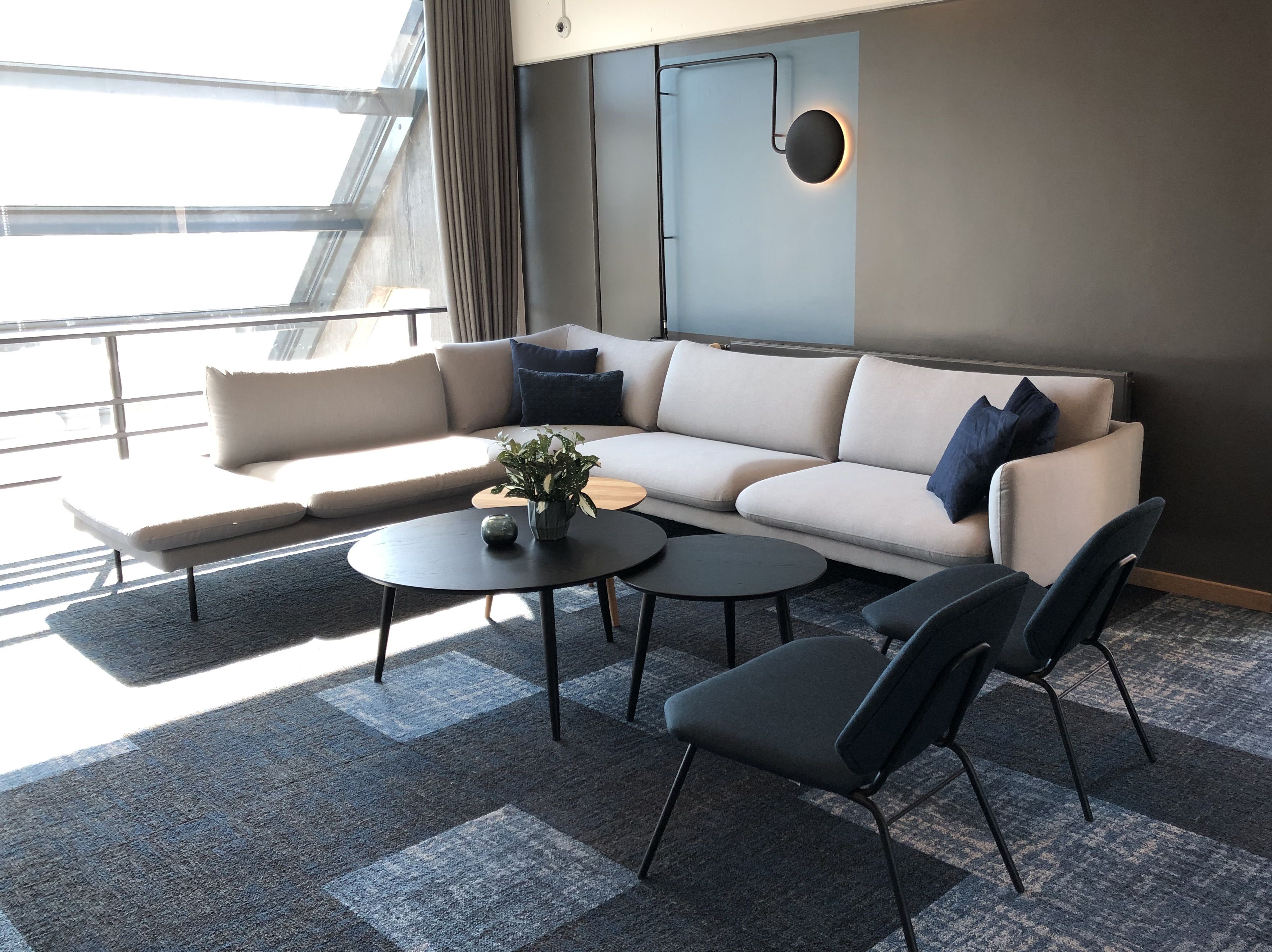 Uma sala de estar moderna com um sofá, duas mesinhas de centro e cadeiras.