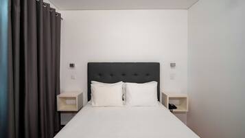 A neatly made bed with white linens, a dark headboard, and two bedside tables with lamps.