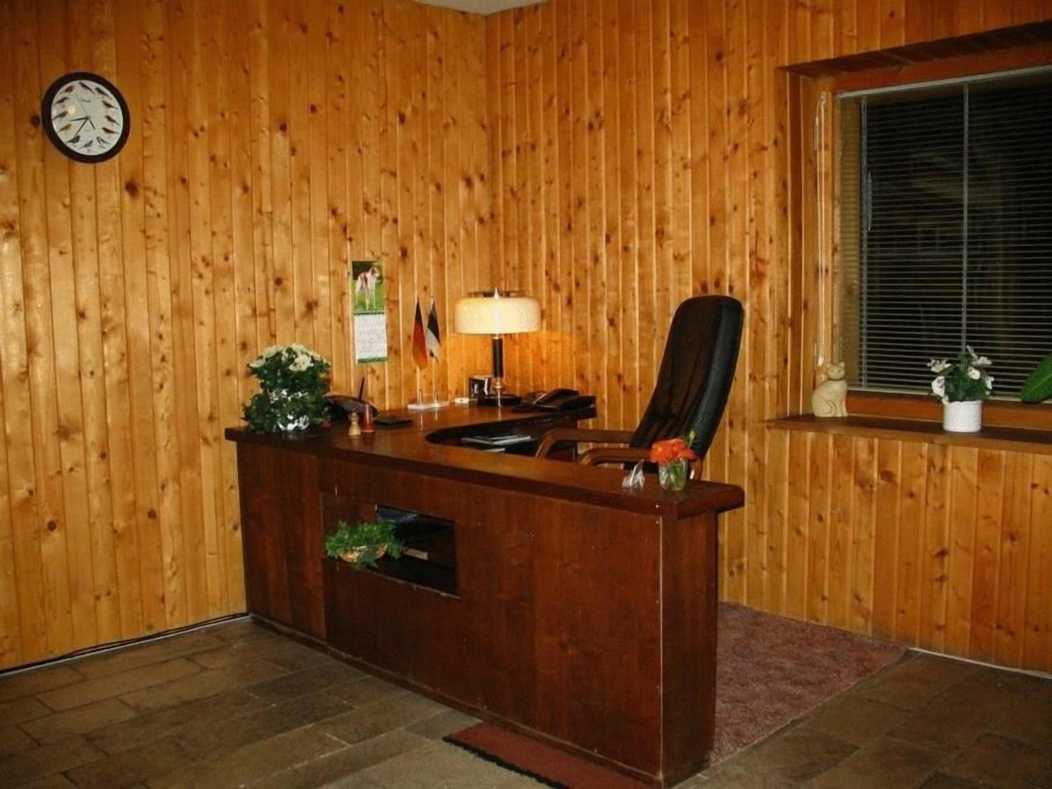 A wooden-paneled room with a reception desk, a clock, and a window with blinds.