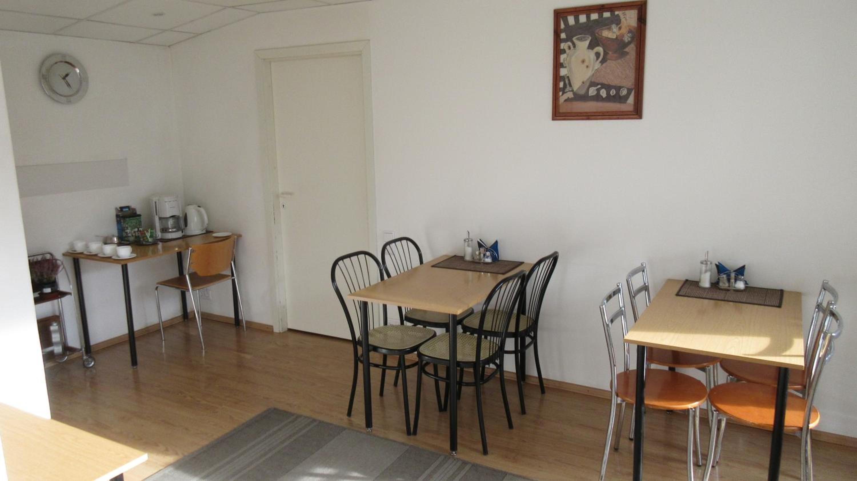 A dining area with a wooden table and chairs, a coffee machine, and a clock on the wall.