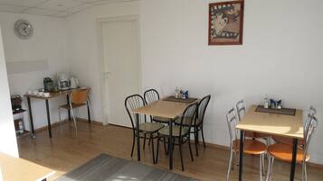 A dining area with a wooden table and chairs, a coffee machine, and a clock on the wall.