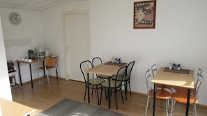A dining area with a wooden table and chairs, a coffee machine, and a clock on the wall. - Nepi Hotell (Tallinn)