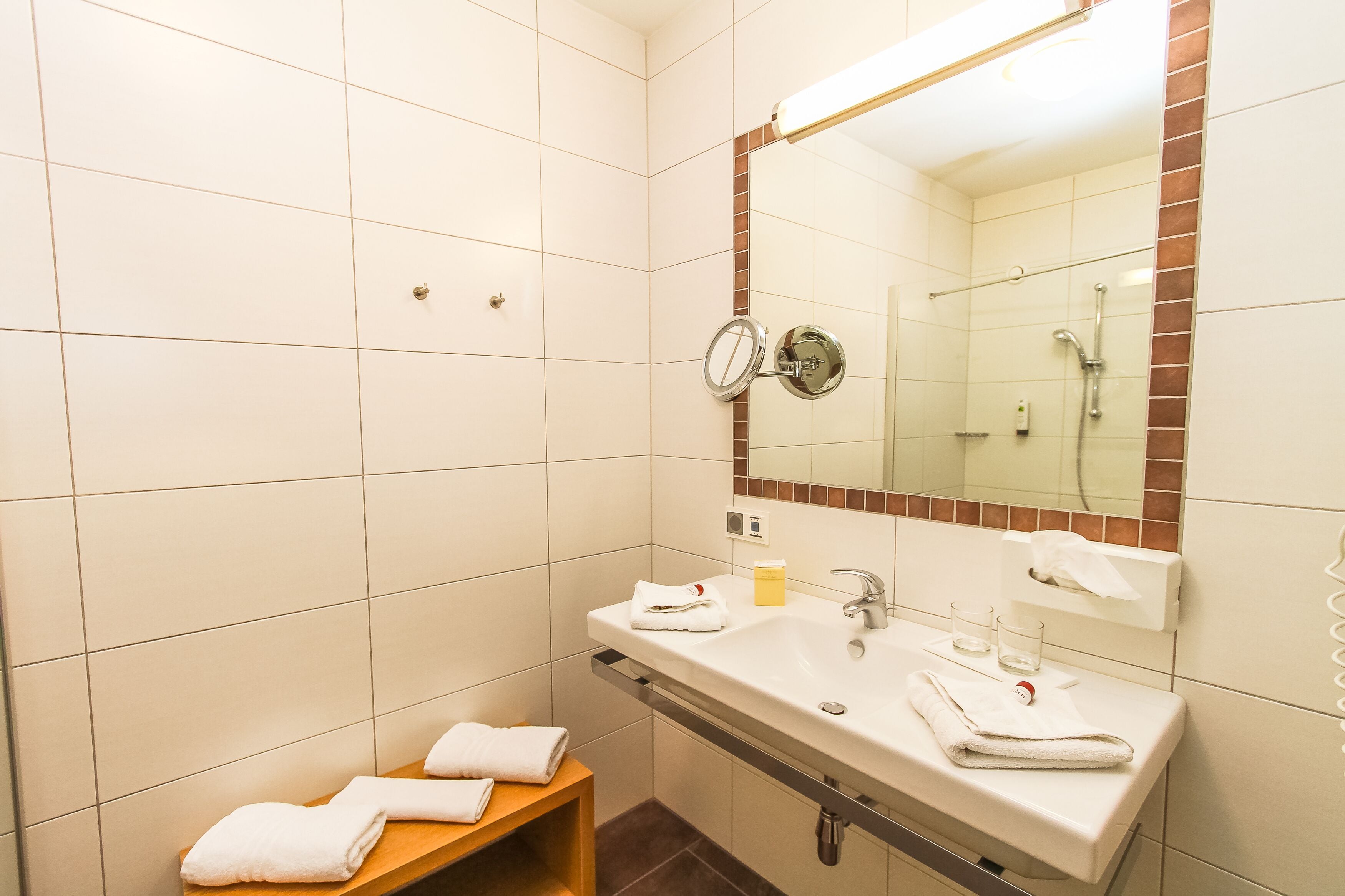 A bathroom with a sink, mirror, towel rack, and a small wooden stool.