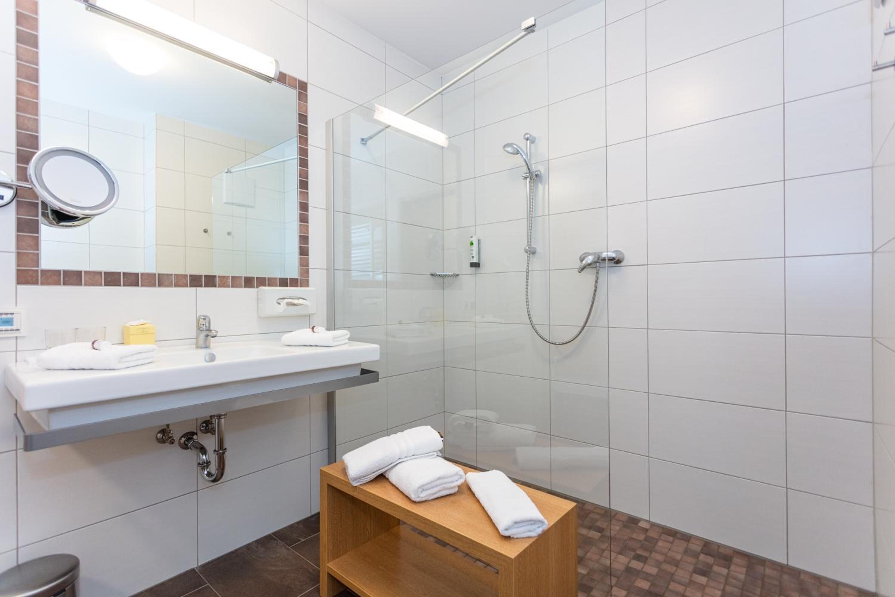 Ein modernes Badezimmer mit Waschbecken, Spiegel und Dusche.