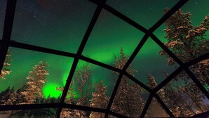 A view through a window with a geometric pattern, displaying a night sky with stars and the aurora borealis. - Kakslauttanen Arctic Resort (Sodankyla)