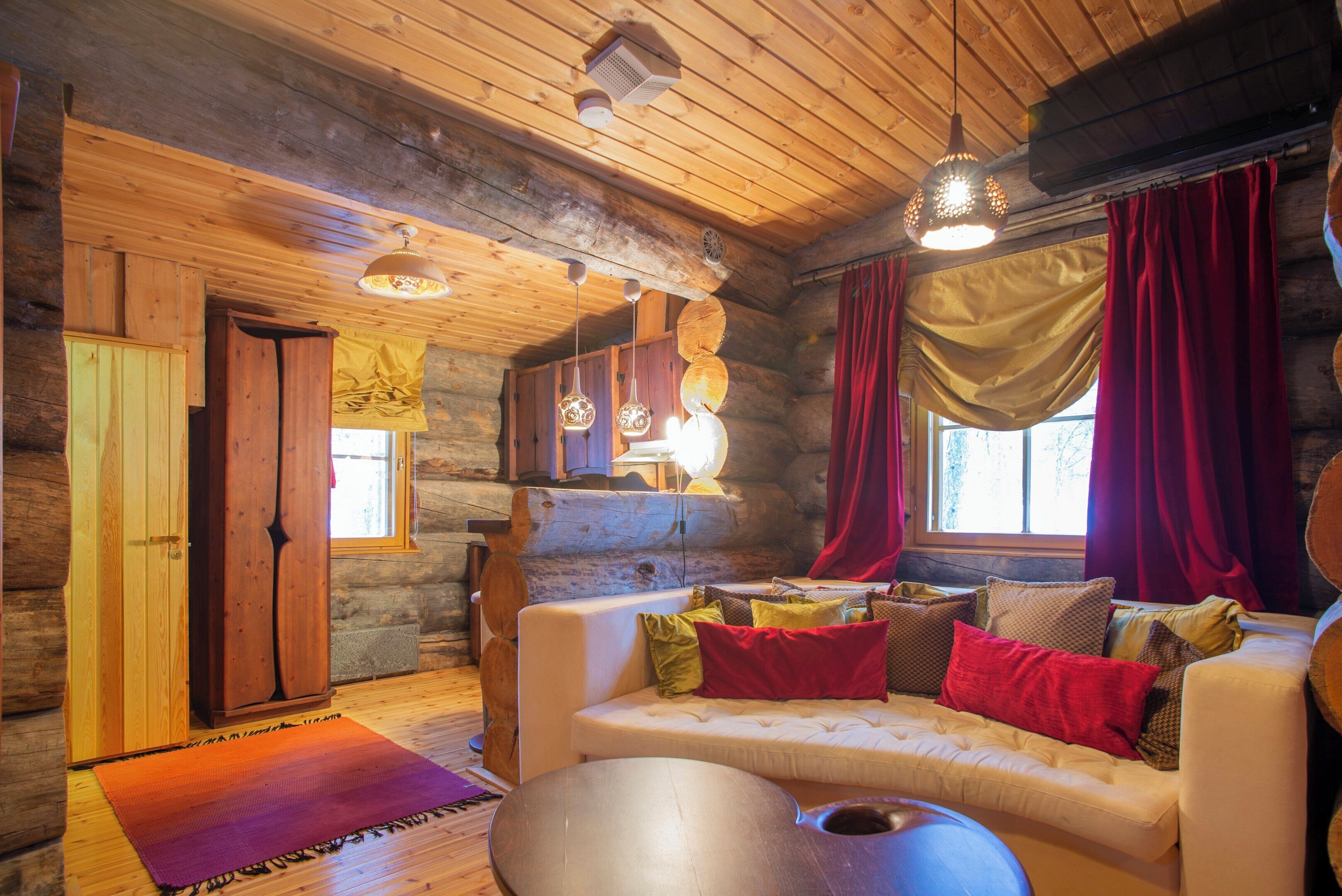 A cozy log cabin interior with a sofa, cushions, and a rug.