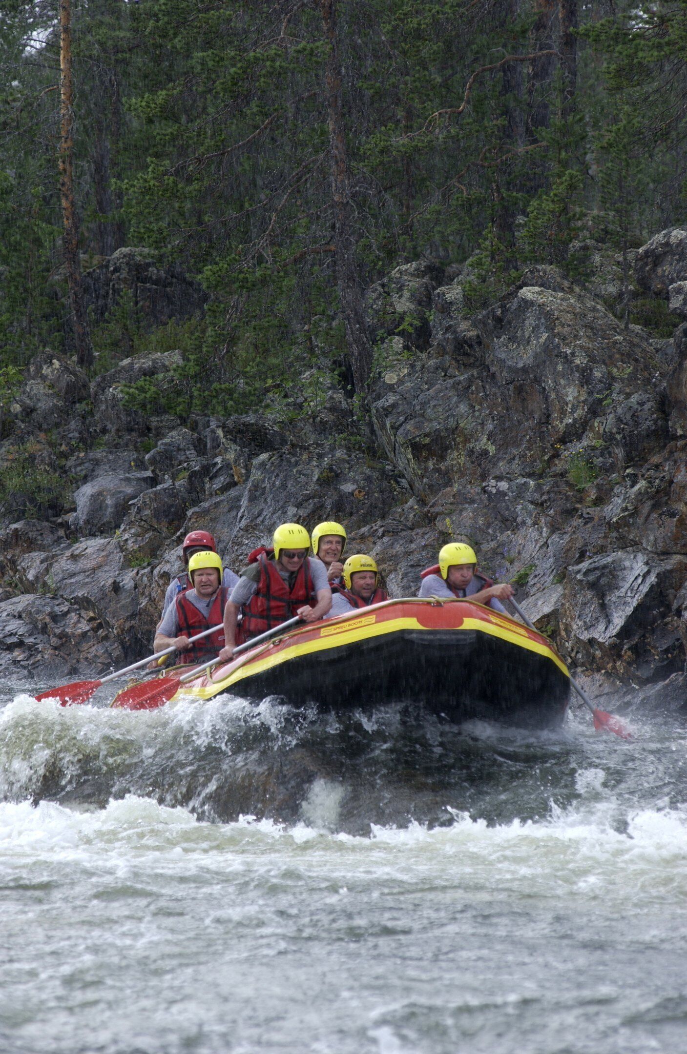 A group of people in a raft navigating a river with rocky banks.