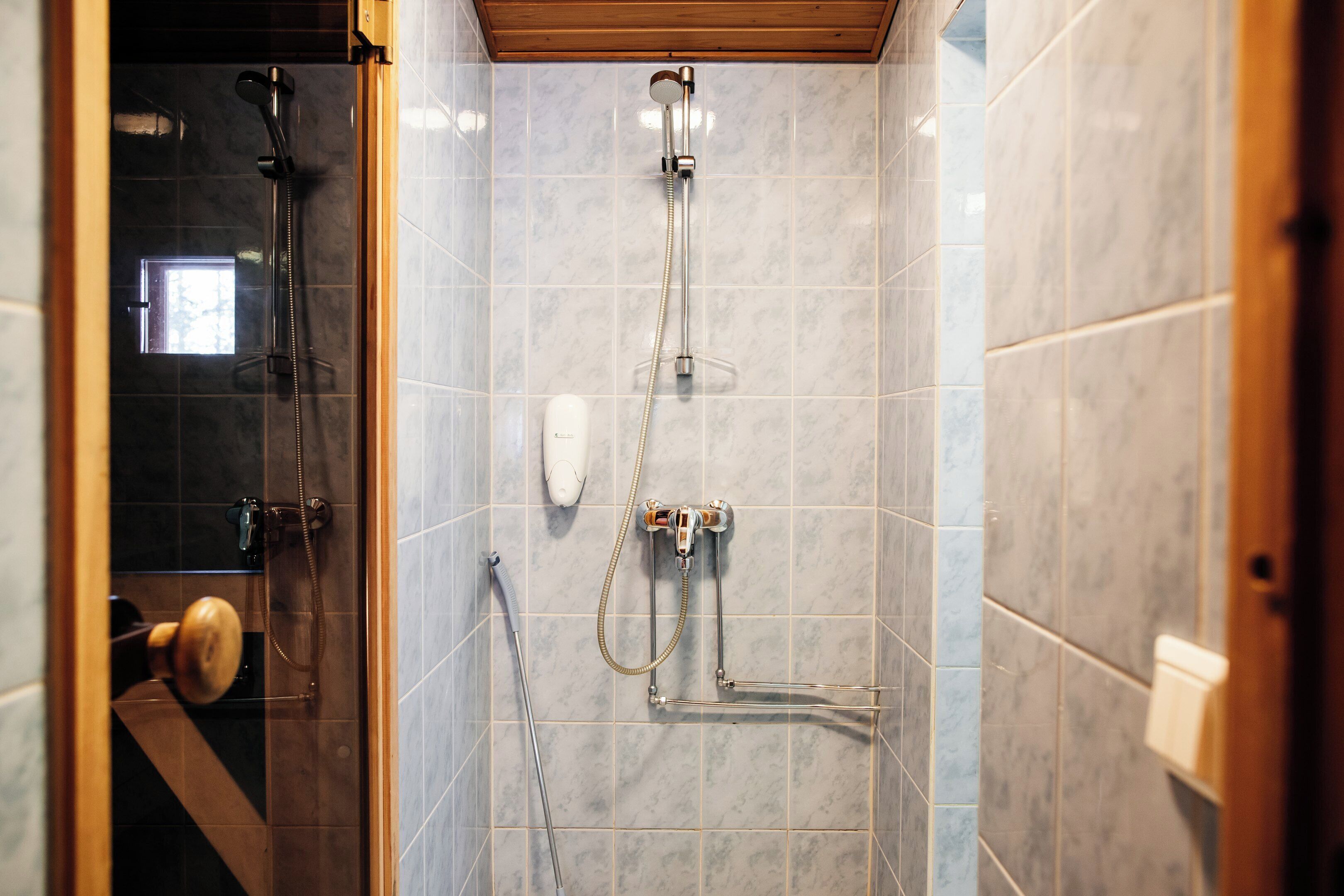 Une douche équipée d’un pommeau de douche à main, d’un robinet mural et d’un flexible de douche à main.