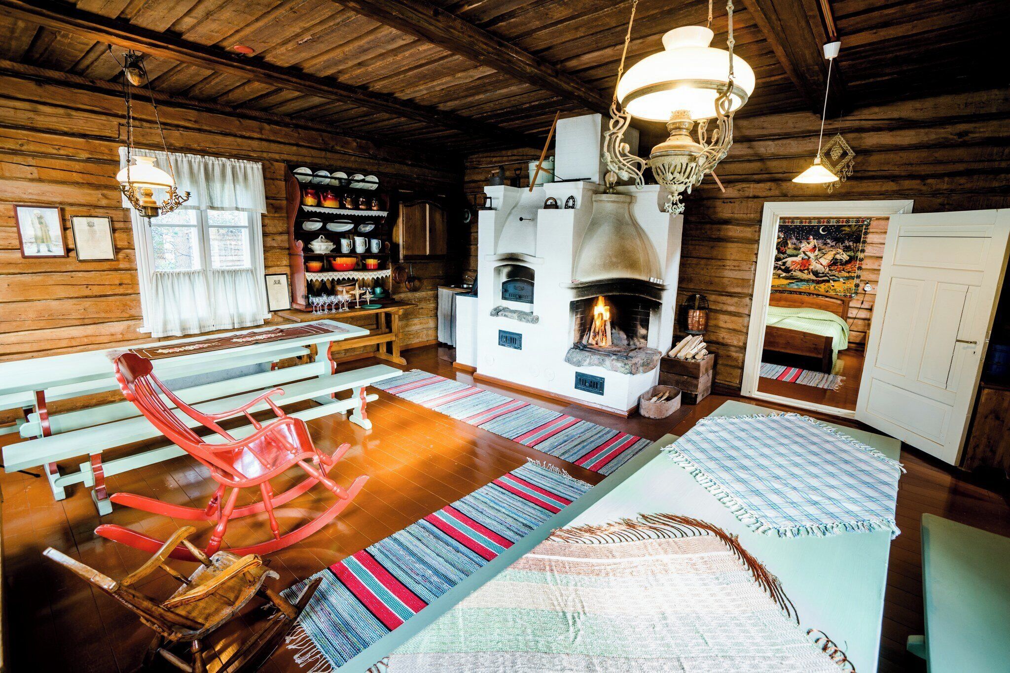 A cozy cabin interior with a fireplace, wooden walls, and a rocking chair.