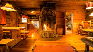 Interior rústico de una cabaña con chimenea de piedra, muebles de madera y un ambiente acogedor.