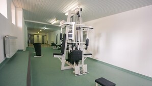 Un gimnasio con equipo de ejercicio, una banca y un radiador.