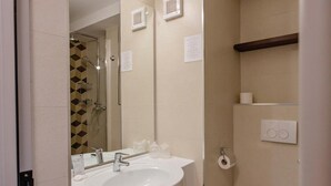 Un baño con lavamanos doble, inodoro, espejo y ducha.