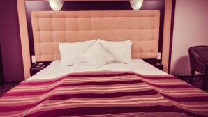 A hotel room with a large bed, a headboard, and a chair. - Ozana (Bistri?a)