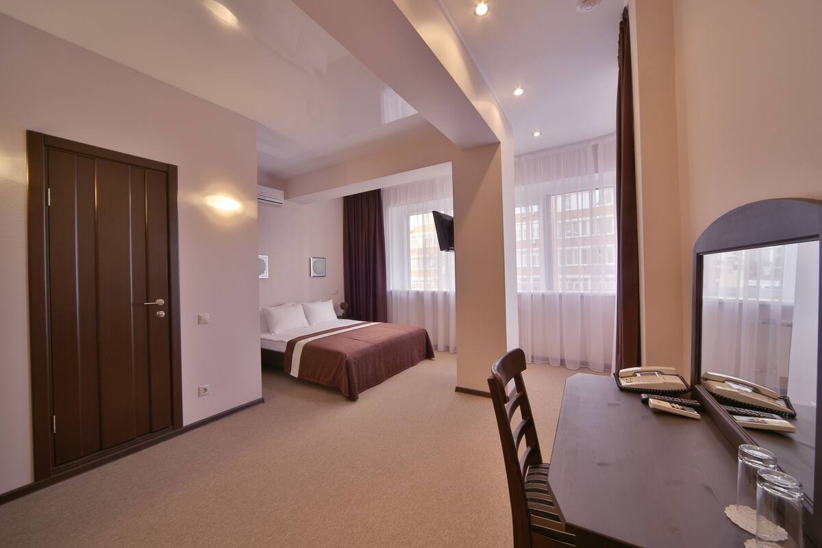 Een hotelkamer met een bed, een bureau met telefoon en een spiegel.
