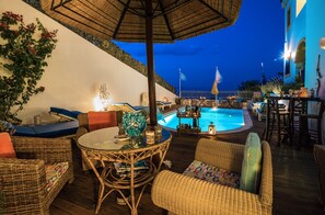 An outdoor pool area with wicker furniture, a bar, and a view of the pool.