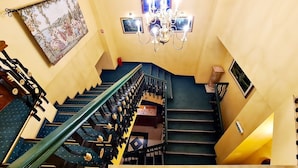 A staircase with a chandelier, a framed picture, and a fire extinguisher.