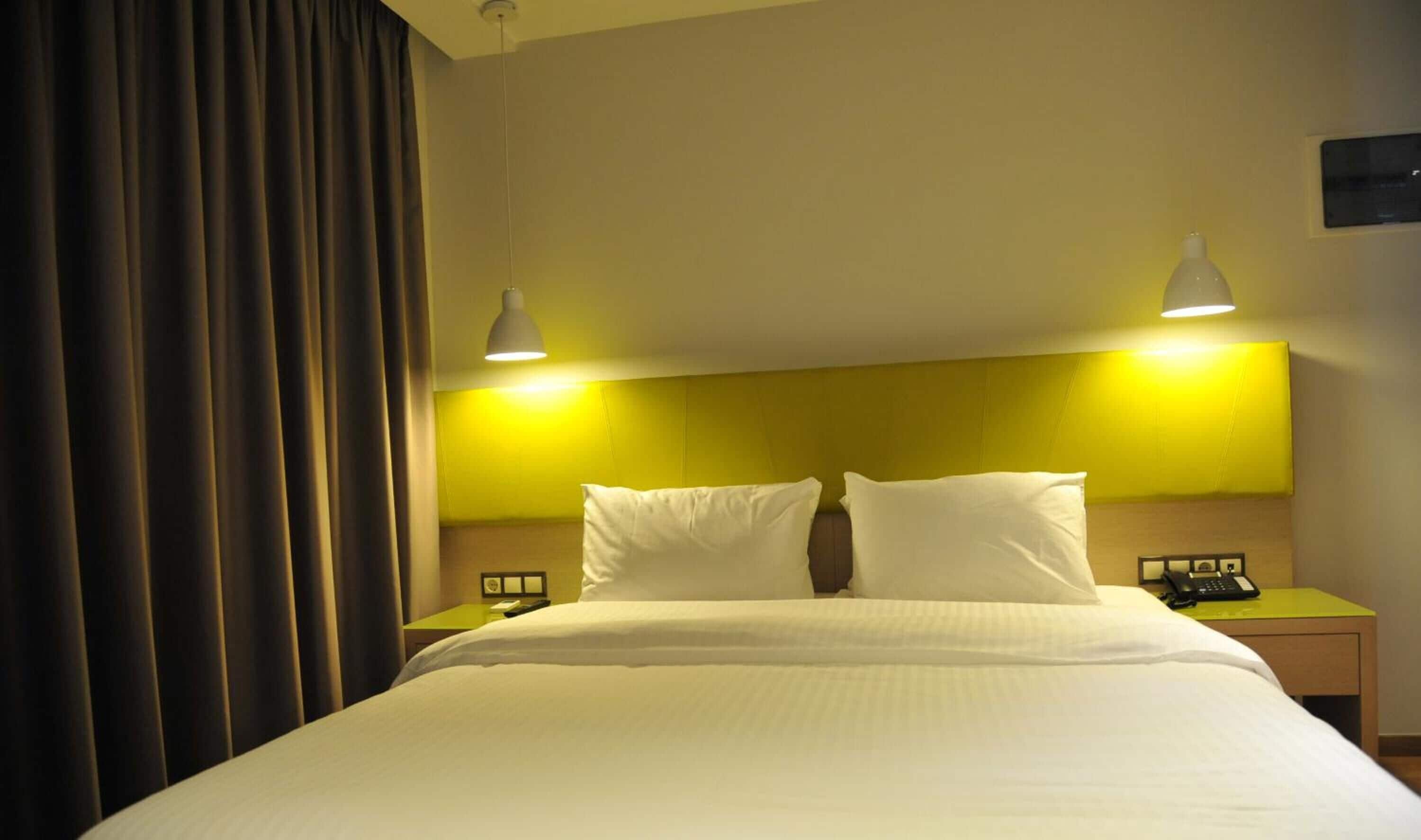 Una habitación de hotel con una cama grande, dos mesitas de noche y un cabecero.