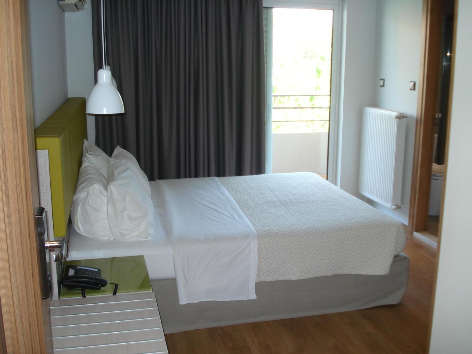 A neatly made bed with white linens, a bedside lamp, and a small table with a telephone.