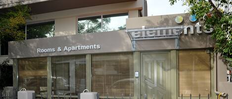 Un immeuble avec une enseigne indiquant « Chambres et appartements » et une entrée fermée par un portail.